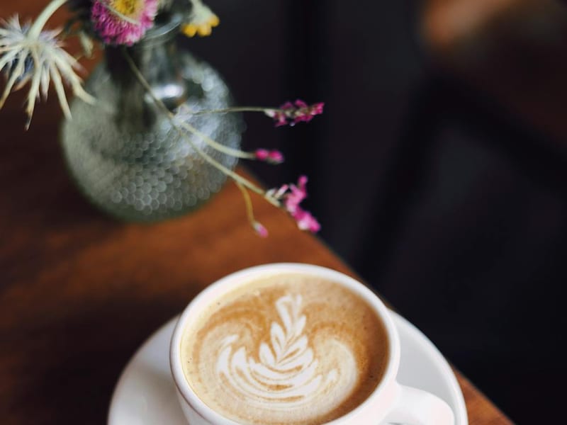 A latte with leaf art on a cafe table